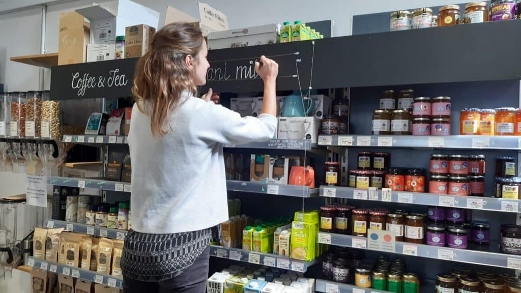 woman writing sign jars shelf real food store